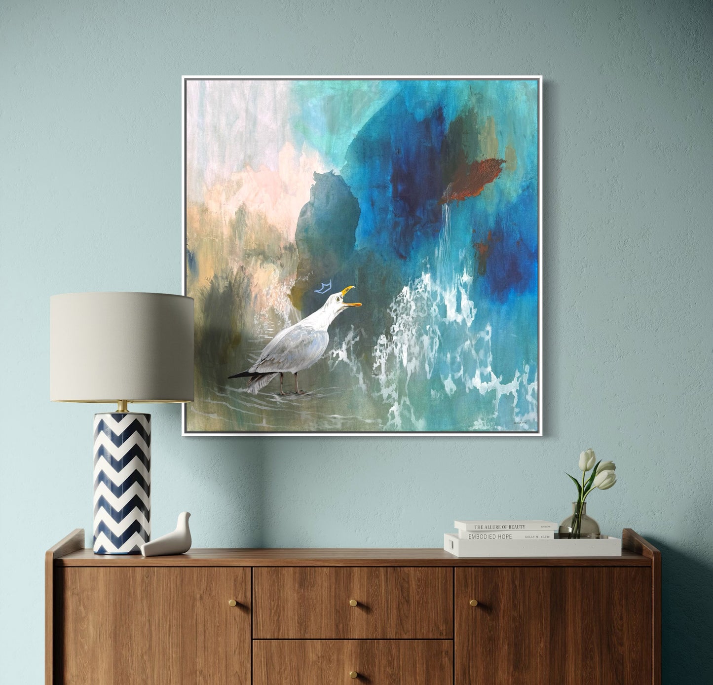 Abstract painting of a crowned seabird painted by Boston area artist Megan Carty on a wall above a modern wooden sideboard with decorative items.