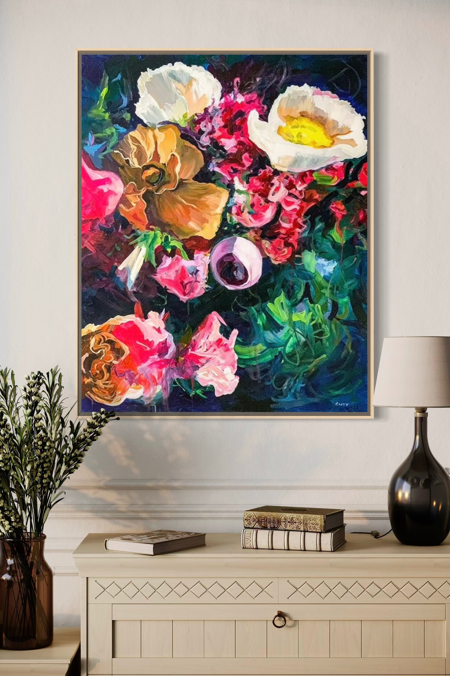 Colorful floral painting wall art print by Megan Carty on a wall above a white cabinet with decorative items.