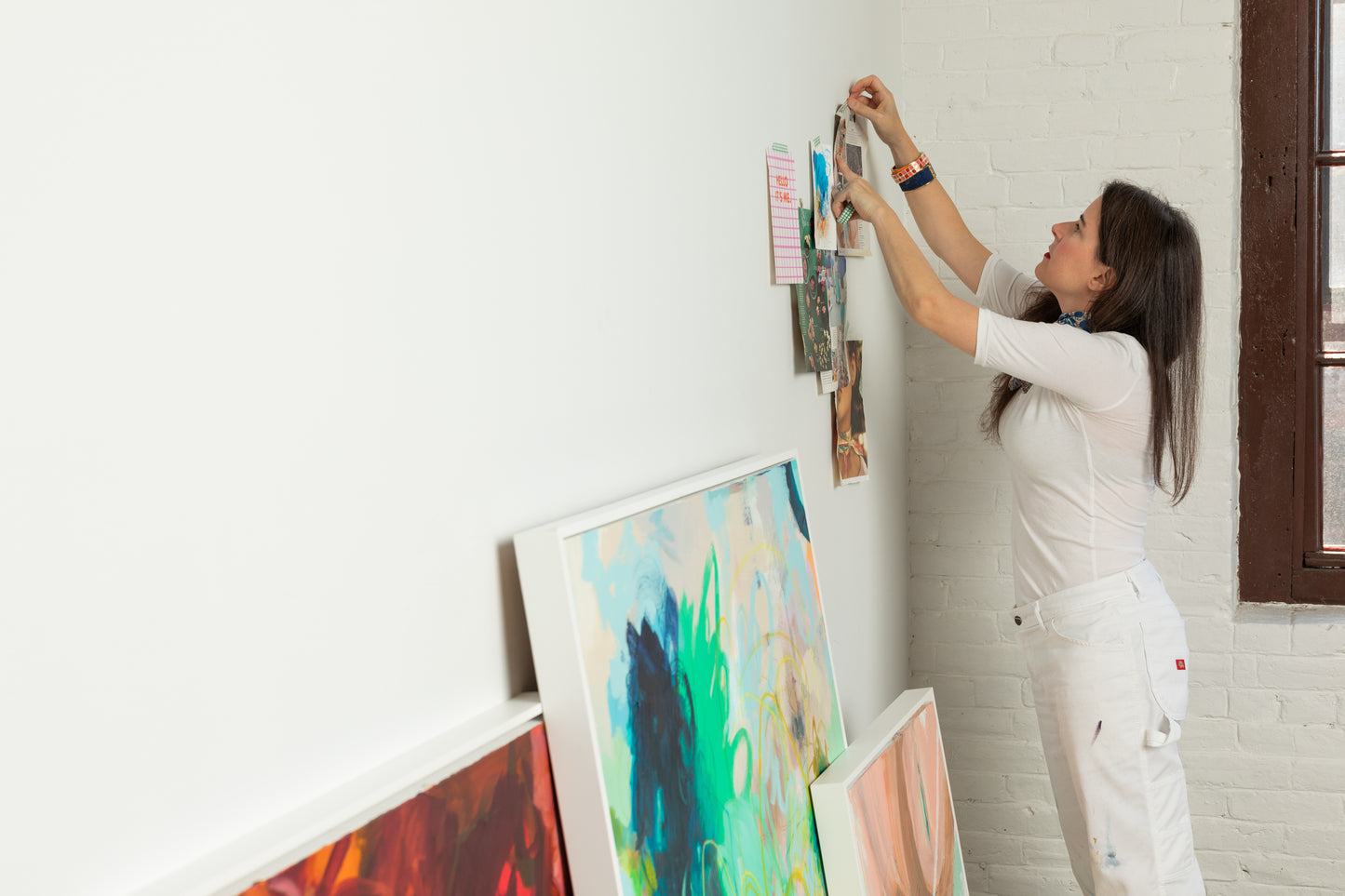 Boston area artist Megan Carty arranging art prints on a white wall