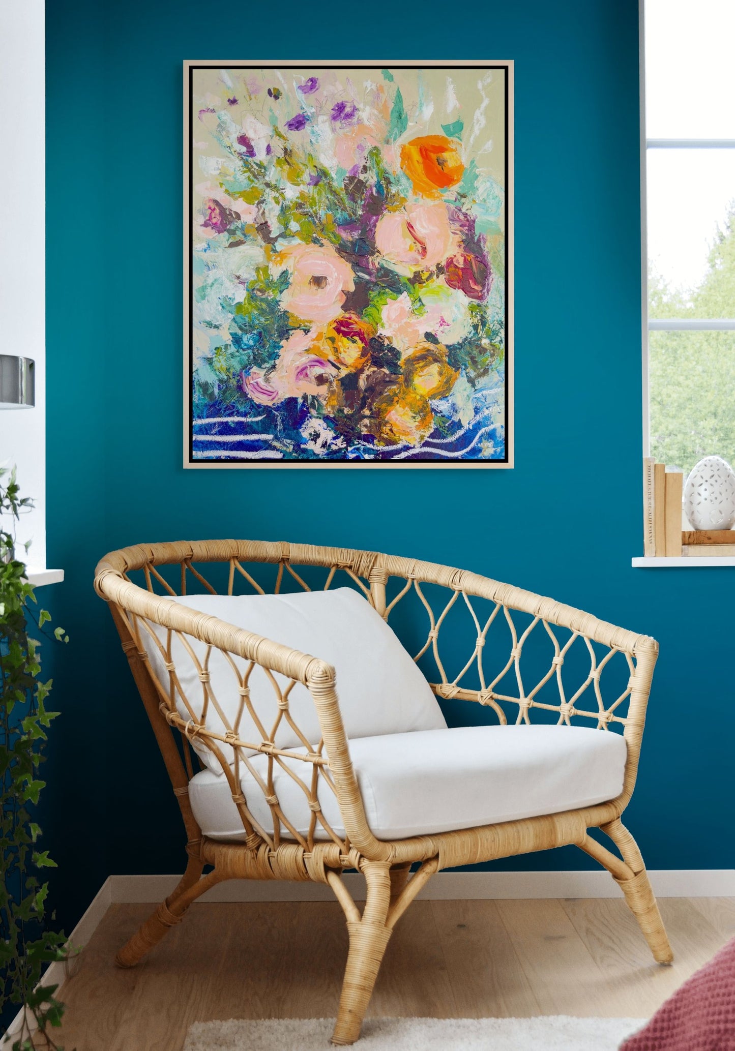 Rattan chair with white cushions in front of a colorful abstract floral painting on a blue wall. Painted by Boston area artist Megan Carty