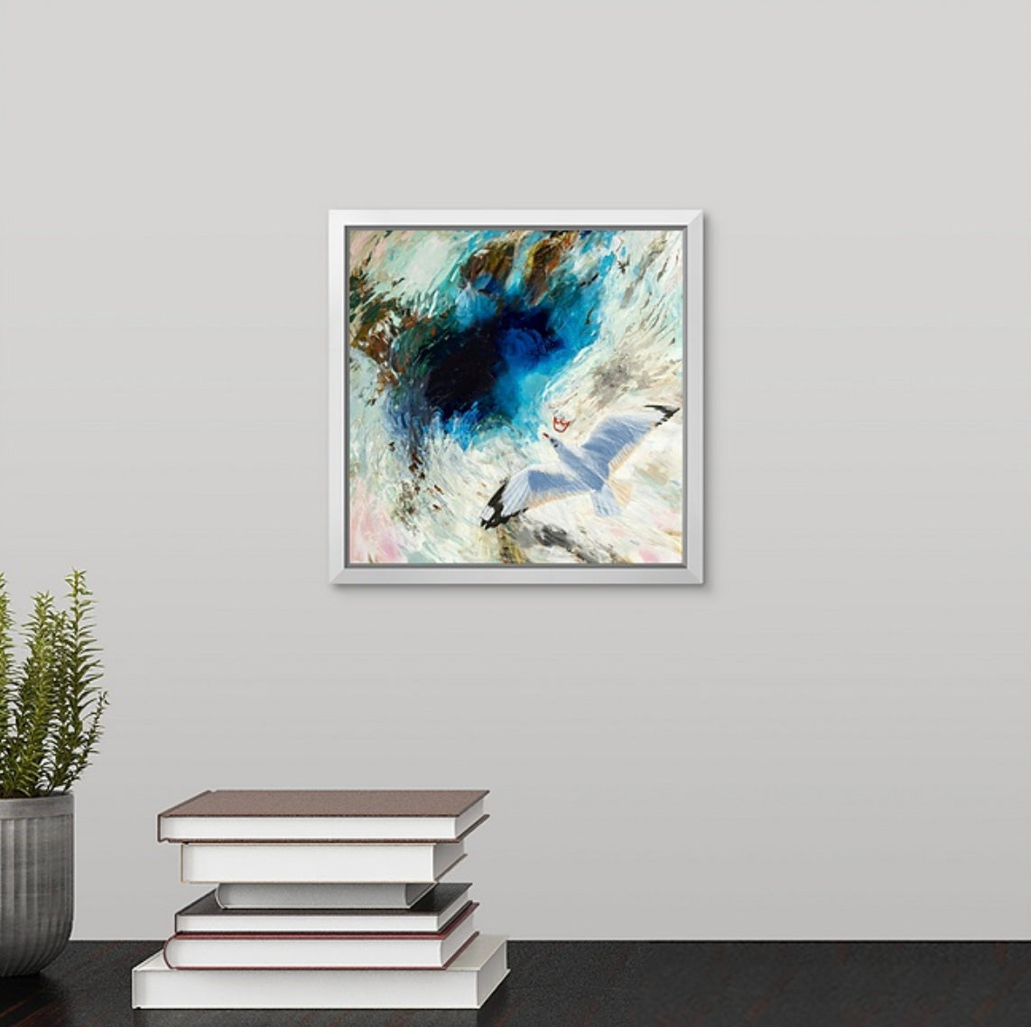 Framed abstract artwork of a crowned seagull flying painted by New England artist Megan Carty, on a wall with books and a plant below.