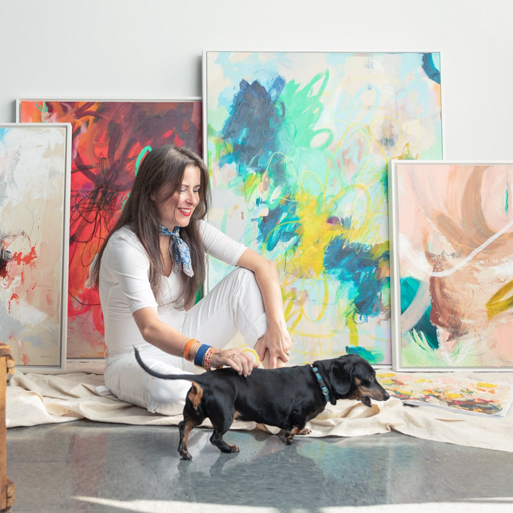 intuitive abstract artist Megan Carty with her dog in her studio surrounded by energetic abstract paintings