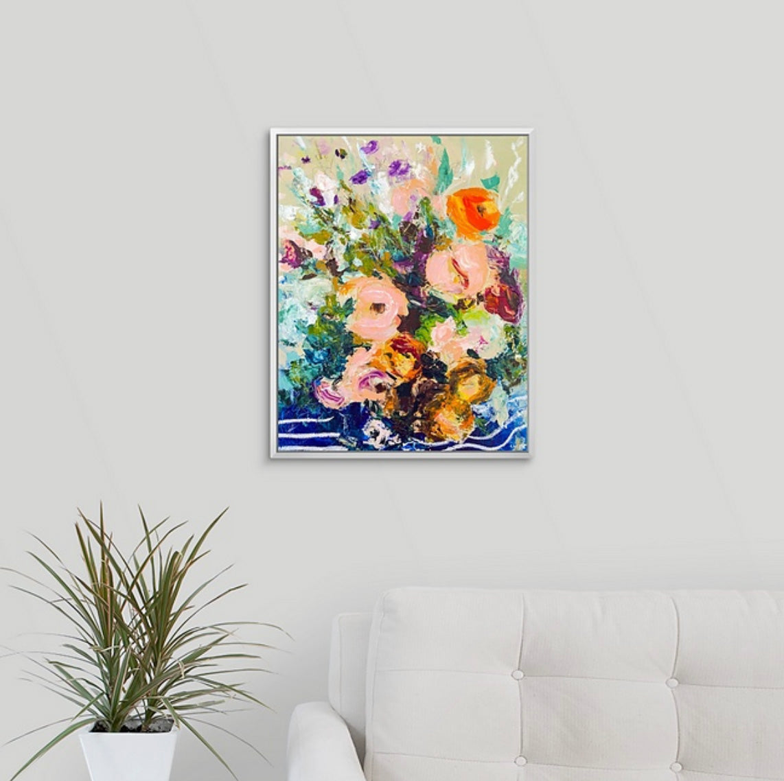 Framed abstract floral painting on a wall above a stack of books with a plant to the left. Painted by New England artist Megan Carty