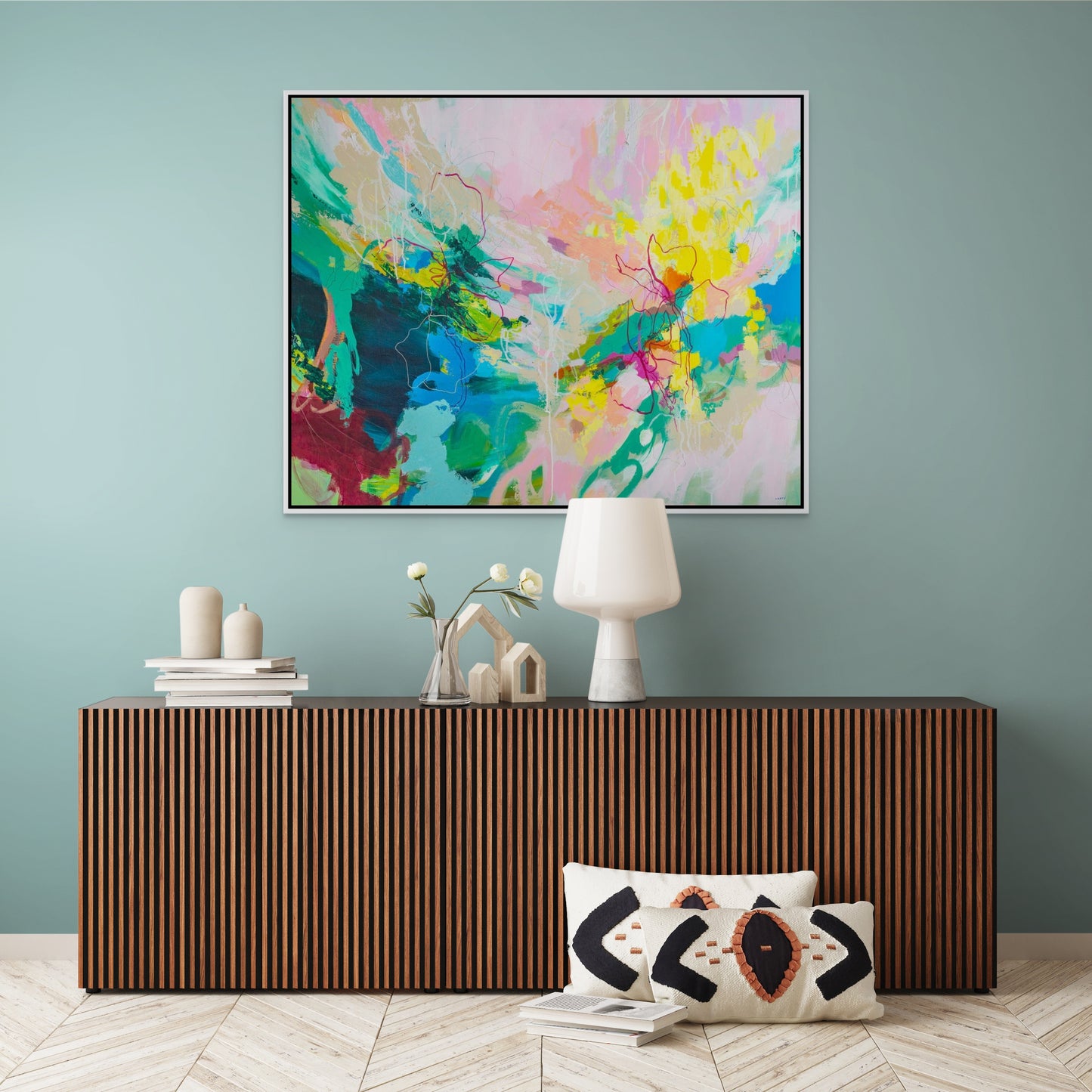 Colorful palm beach vibes intuitive abstract painting by Boston area artist Megan Carty on a gray wall with a stack of books and a plant below.