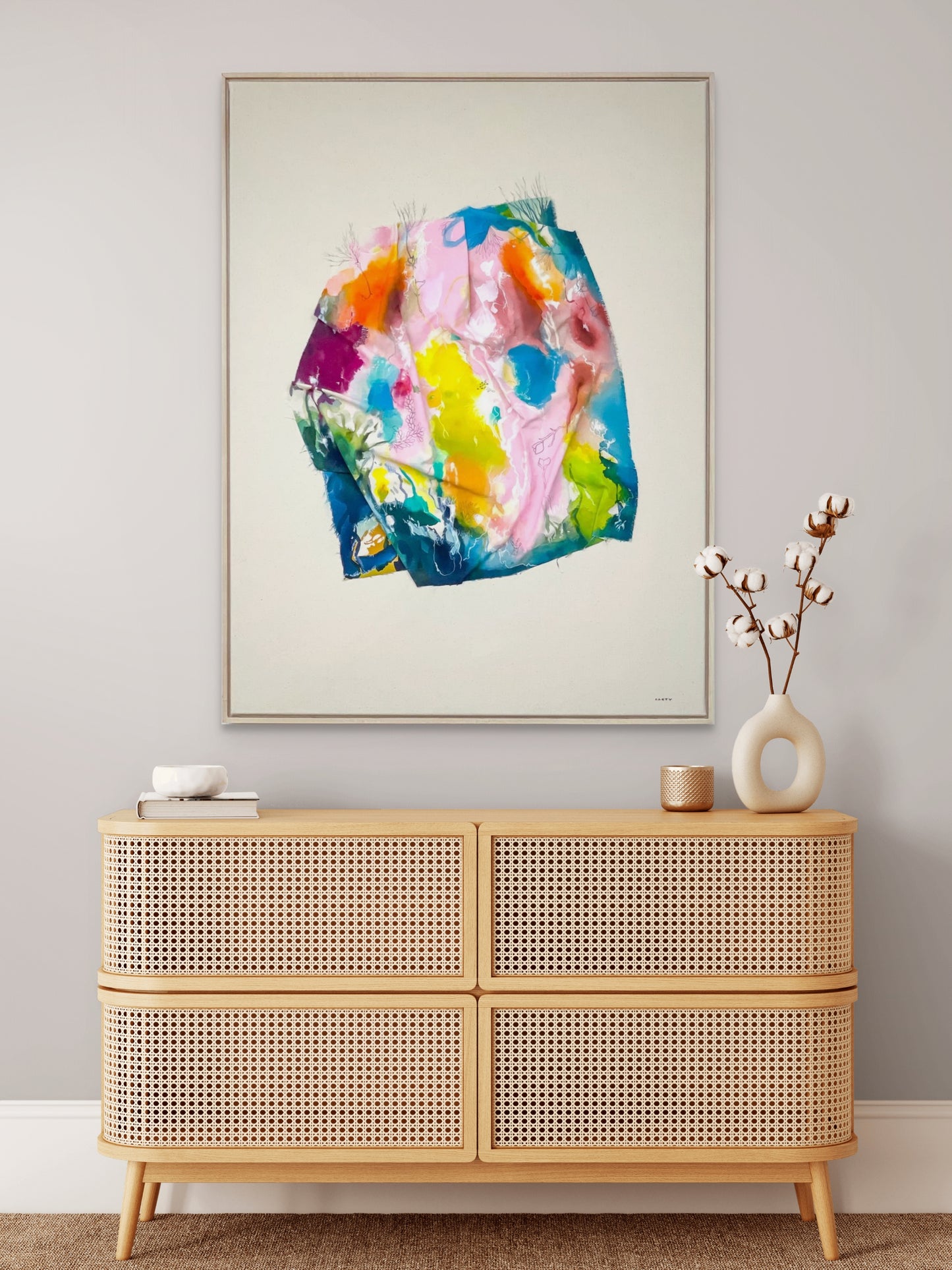 Colorful abstract landscape painting by New England artist Megan Carty above a wooden cabinet with decorative items.