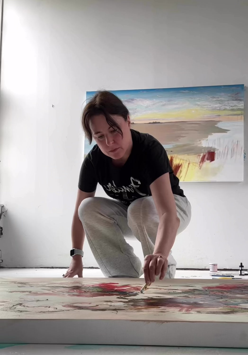 New England artist Megan Carty in her studio painting an intuitive abstract painting using acrylic paints and oil pastels.