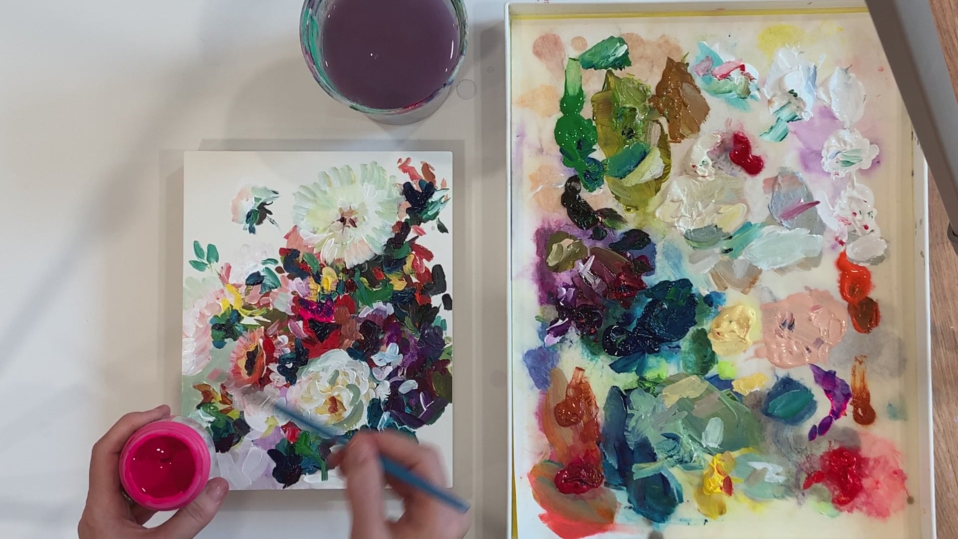 Megan Carty painting a small abstract floral painting with a palette of paint and water jug nearby.