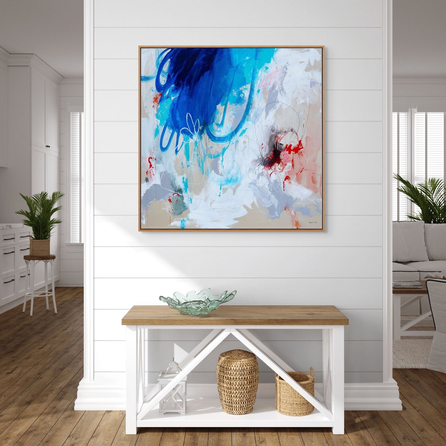 Modern coastal style living room with large blue abstract art on the wall and a wooden bench. Art by Boston artist Megan Carty. Beach house art or chic modern art for urban apartment.