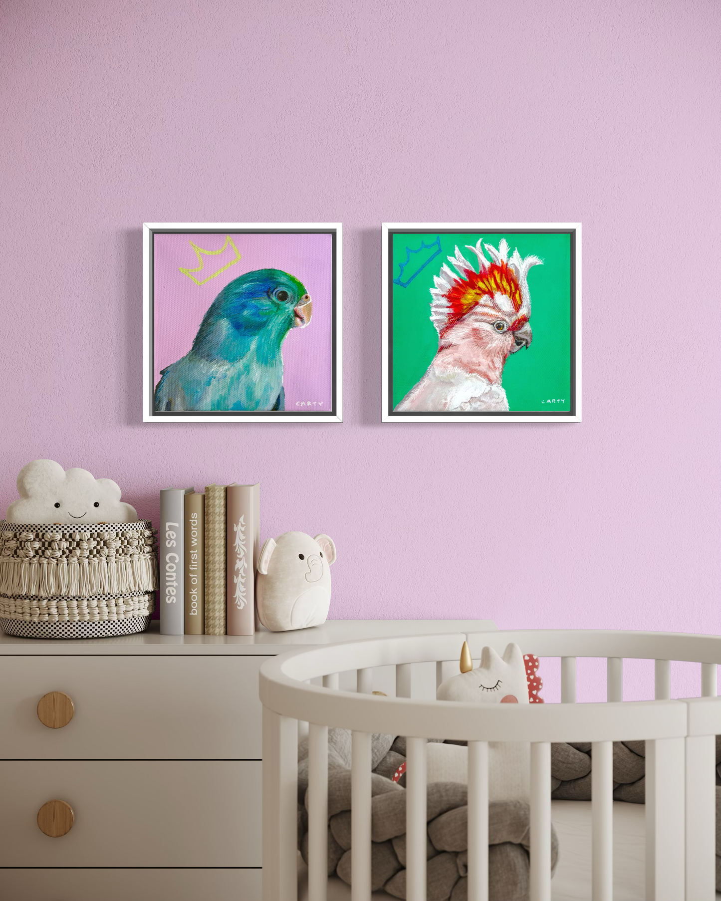 Two framed paintings of parrots on a pink wall above a dresser and crib. Painted by Megan Carty