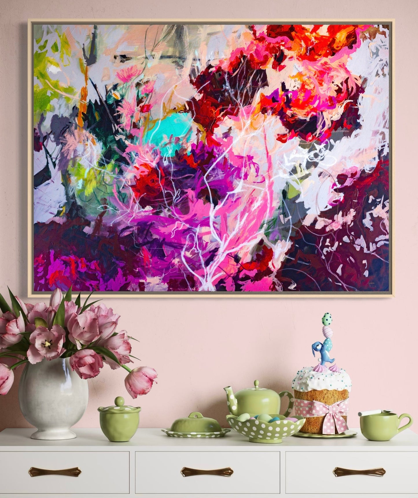 Colorful abstract landscape painting above a white console table with decorative items.